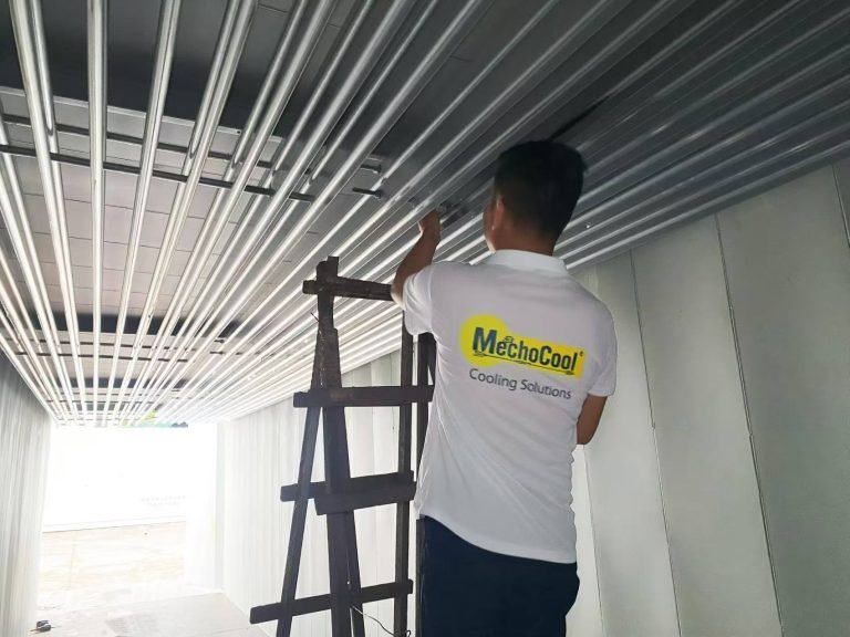 Technician inspecting the ceiling evaporator inside a container cold room